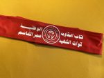 Red polyester tie-back headband featuring the emblem and Arabic script of the National Resistance Brigades, Martyr Omar Al-Qassem Forces, affiliated with the Democratic Front for the Liberation of Palestine (DFLP).