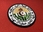 This patch features the emblem of the National Liberation Front (FLN) of Algeria, with intricate Arabic text, a flame, star, crescent, and a sunburst design. Measuring 3.5 inches in diameter, this patch is available with Velcro backing, iron-on backing, or no backing for sewing, making it a versatile addition to any collection. Ideal for collectors, reenactors, and historians.