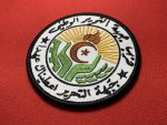 This patch features the emblem of the National Liberation Front (FLN) of Algeria, with intricate Arabic text, a flame, star, crescent, and a sunburst design. Measuring 3.5 inches in diameter, this patch is available with Velcro backing, iron-on backing, or no backing for sewing, making it a versatile addition to any collection. Ideal for collectors, reenactors, and historians.`