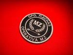Round 3.5-inch embroidered GPO Flechas Operativa MZ patch with white stitching on a black background, featuring the letters “MZ,” laurel branches, and an arrow, displayed on red fabric.