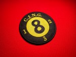 Embroidered round CJNG eight ball patch with black background, yellow “8” center, “C.J.N.G.” at the top, and the numbers 1, 2, and 3 stitched around the outer edge, displayed on a red fabric background.