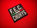 Black rectangular F.E.C. CHUKYS patch replica with white lettering and a horizontal green, white, and red center stripe, associated with Los Chukys and the Cártel del Noreste in northeastern Mexico.