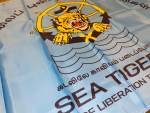 Sea Tigers LTTE flag with roaring tiger emblem inside ship wheel and anchor, Tamil text “தமிழீழ விடுதலைப் புலிகள்” and “கடலிலே காவியம் படைப்போம்,” ocean waves, and light blue background, 3x5 polyester banner