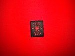 Black Falange Española replica patch featuring the red yoke and five arrows emblem, displayed on red fabric.