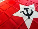 Angled close-up of the black hammer and sickle within a white star on the red Chinese Red Army reproduction flag.