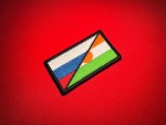 Angled view of a Russia–Niger cooperation flag replica patch with a black embroidered border on red fabric.